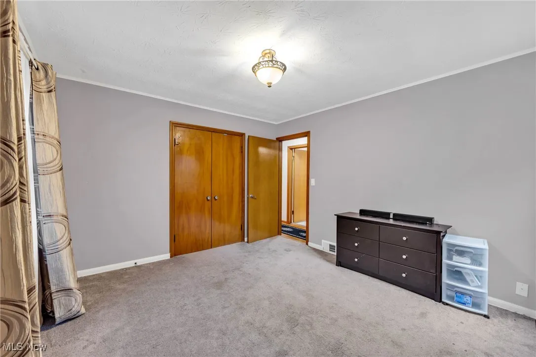 Unfurnished bedroom with carpet flooring, a closet, and crown molding