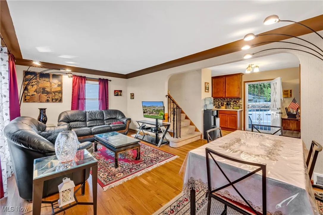 Living area with arched walkways, light wood-style flooring, and stairway