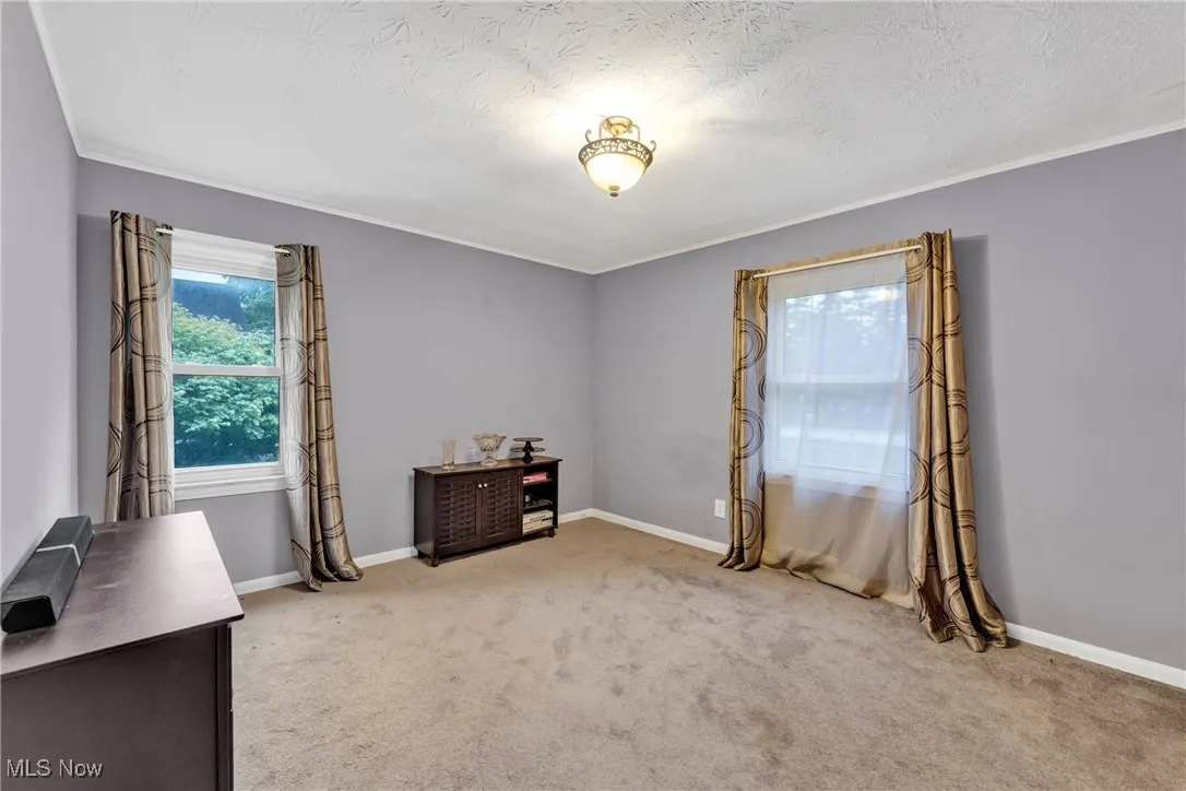 Carpeted office featuring ornamental molding and a textured ceiling
