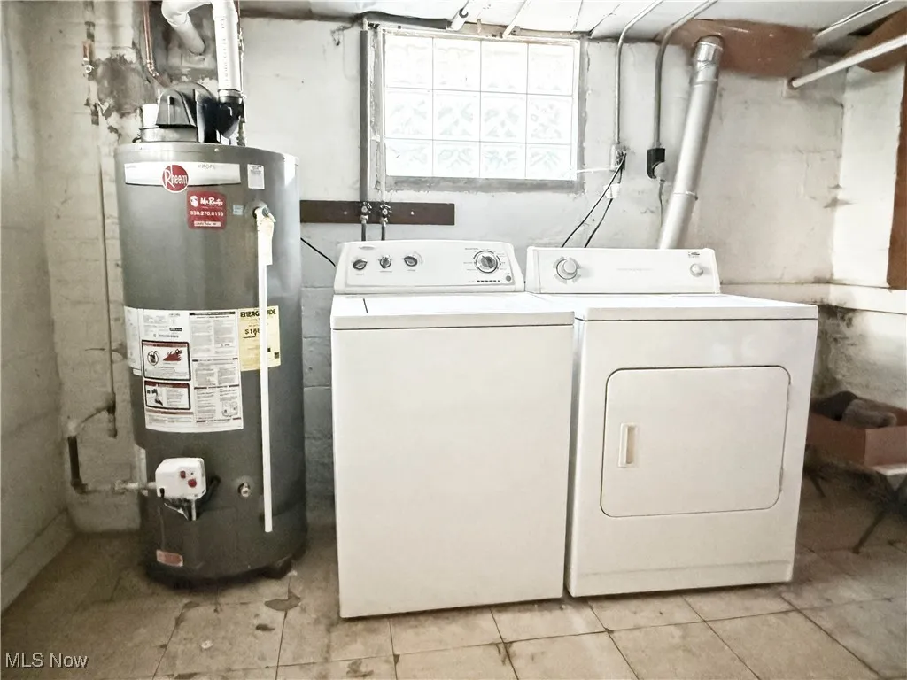 Washroom with gas water heater, independent washer and dryer, and light tile patterned floors