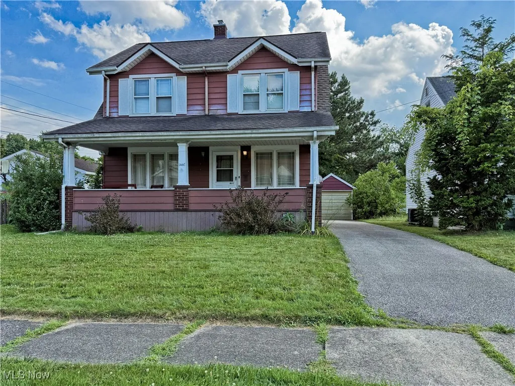 View of front facade with an outdoor structure, covered porch, a front lawn, a chimney, and a shingled roof
