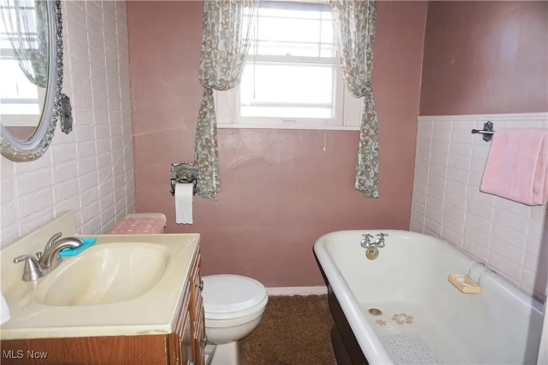 Full bath with tile walls, a freestanding bath, and vanity