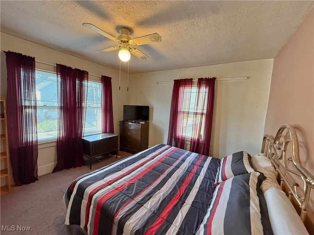 Carpeted bedroom featuring a textured ceiling and ceiling fan