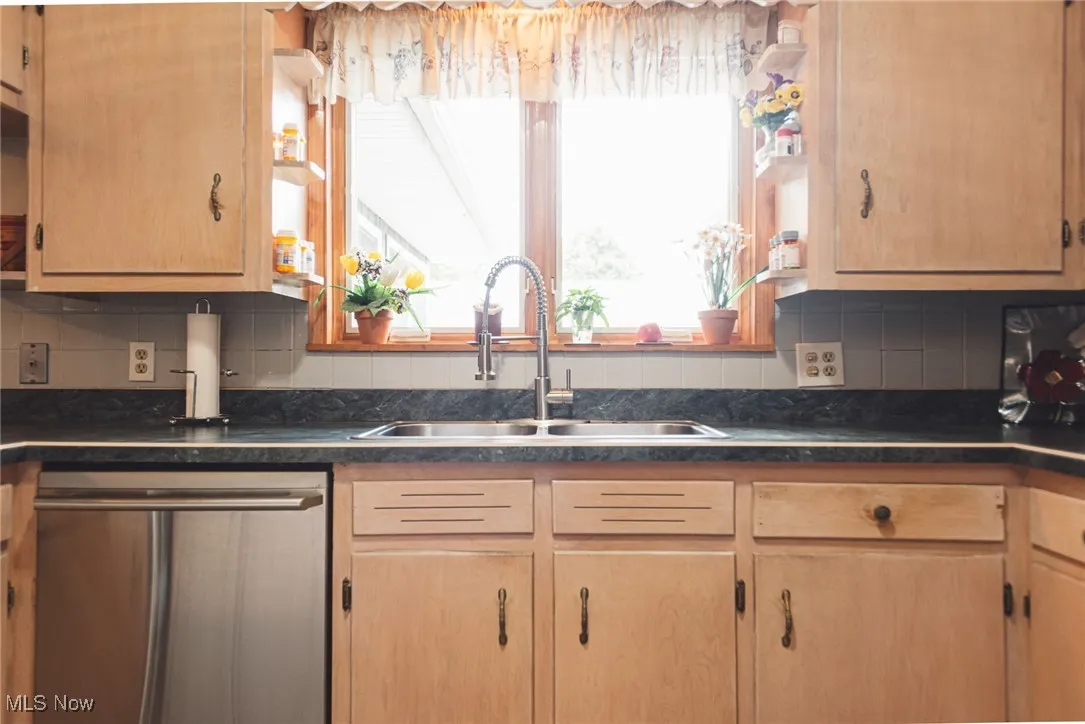 Kitchen featuring backsplash, dishwasher, and light brown cabinetry