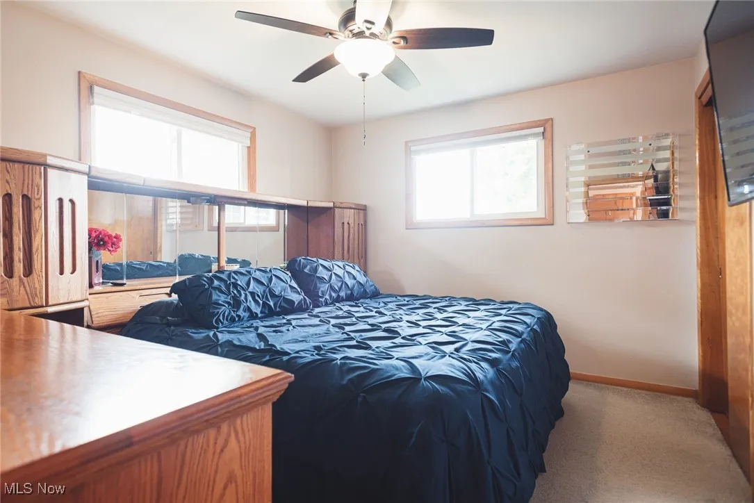 Carpeted bedroom featuring a ceiling fan and baseboards