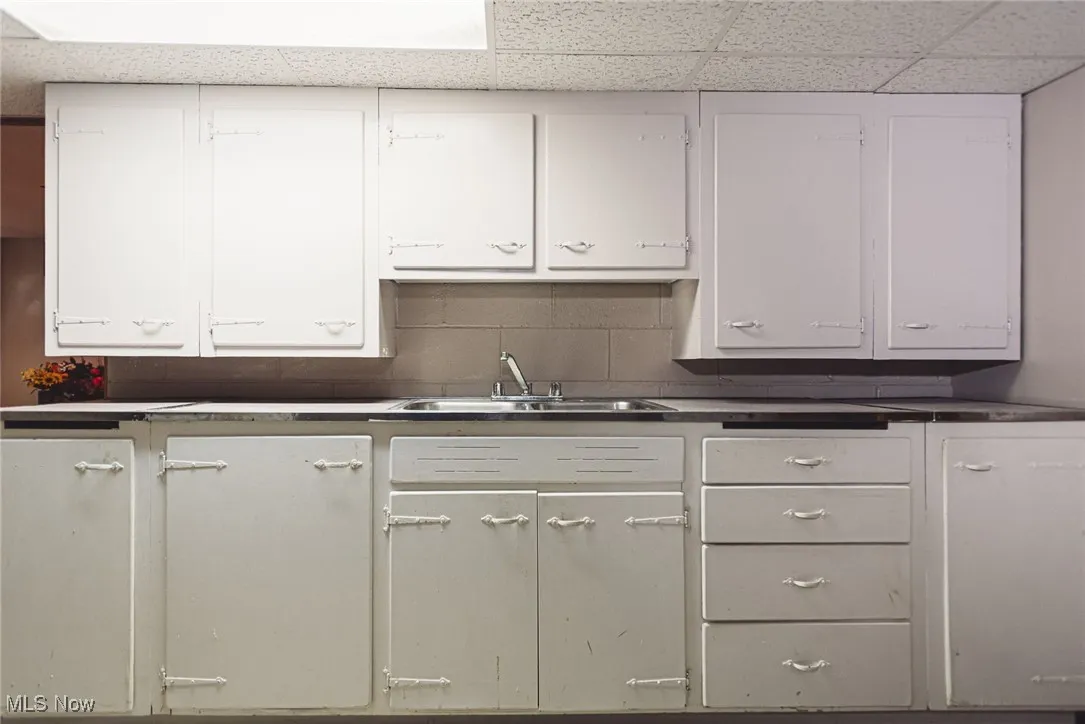 Kitchen featuring a drop ceiling and white cabinetry