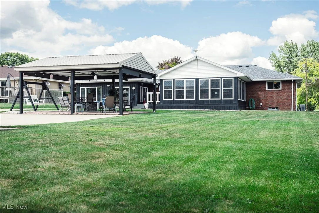 Rear view of property featuring a patio, a lawn, and brick siding