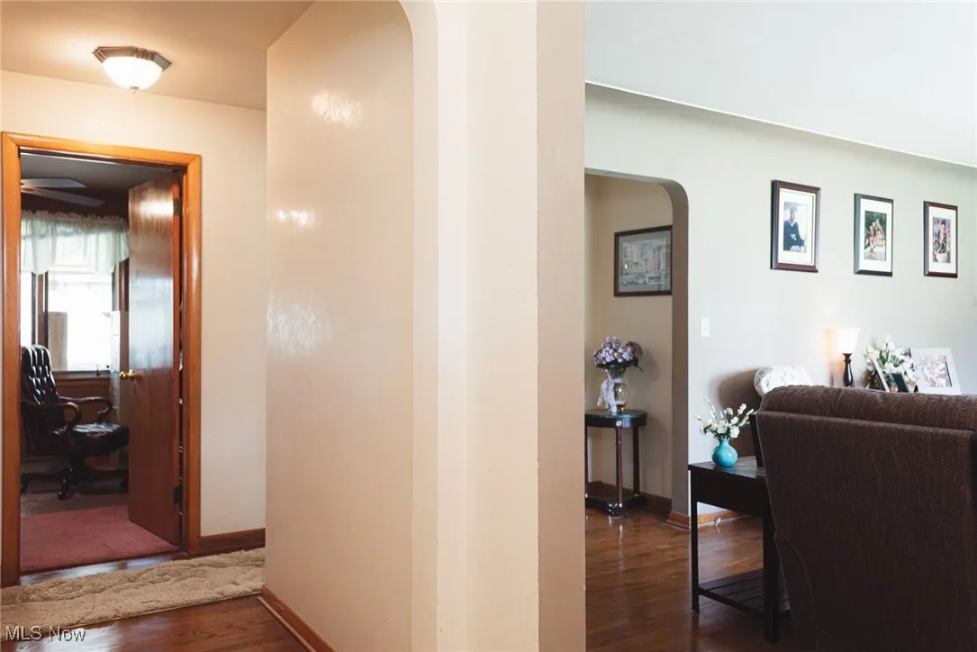 Hallway with arched walkways and dark wood finished floors