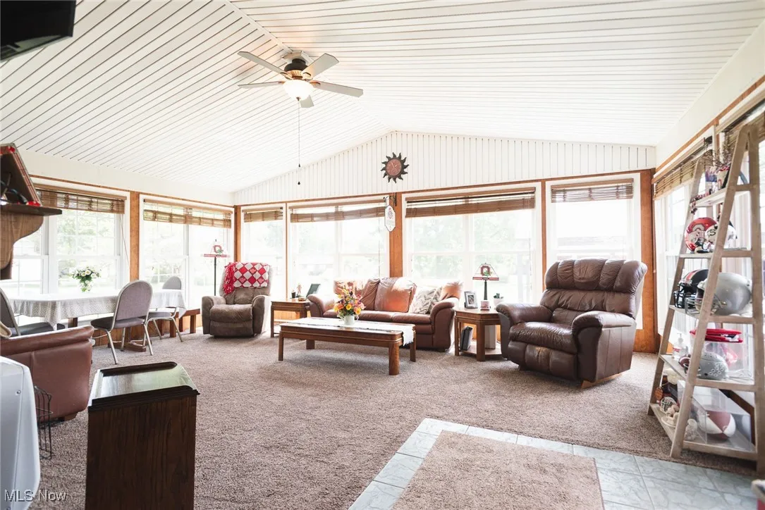 Sunroom with vaulted ceiling, healthy amount of natural light, and carpet flooring