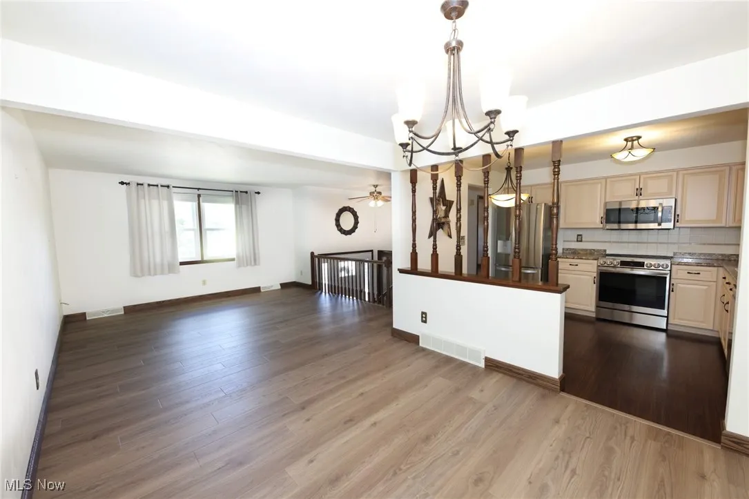 Kitchen featuring open floor plan, appliances with stainless steel finishes, backsplash, a chandelier, and decorative light fixtures