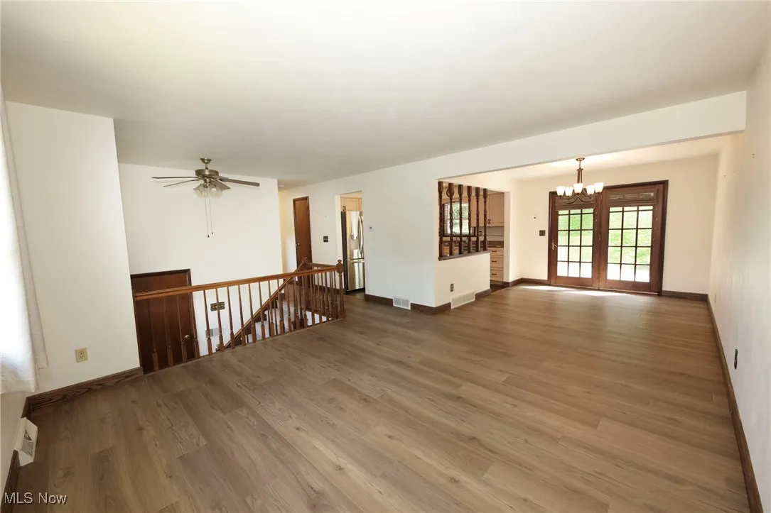 Unfurnished room with wood finished floors, a chandelier, and a ceiling fan