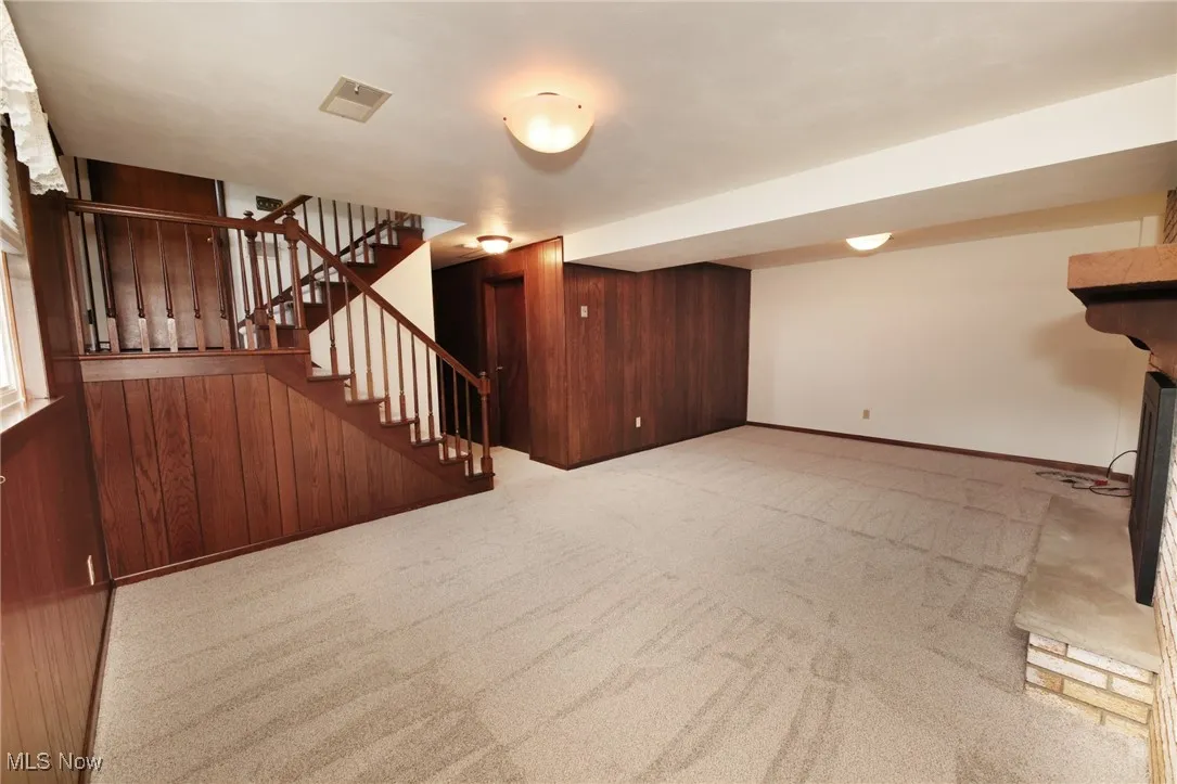 Finished below grade area with wooden walls, stairs, and light colored carpet