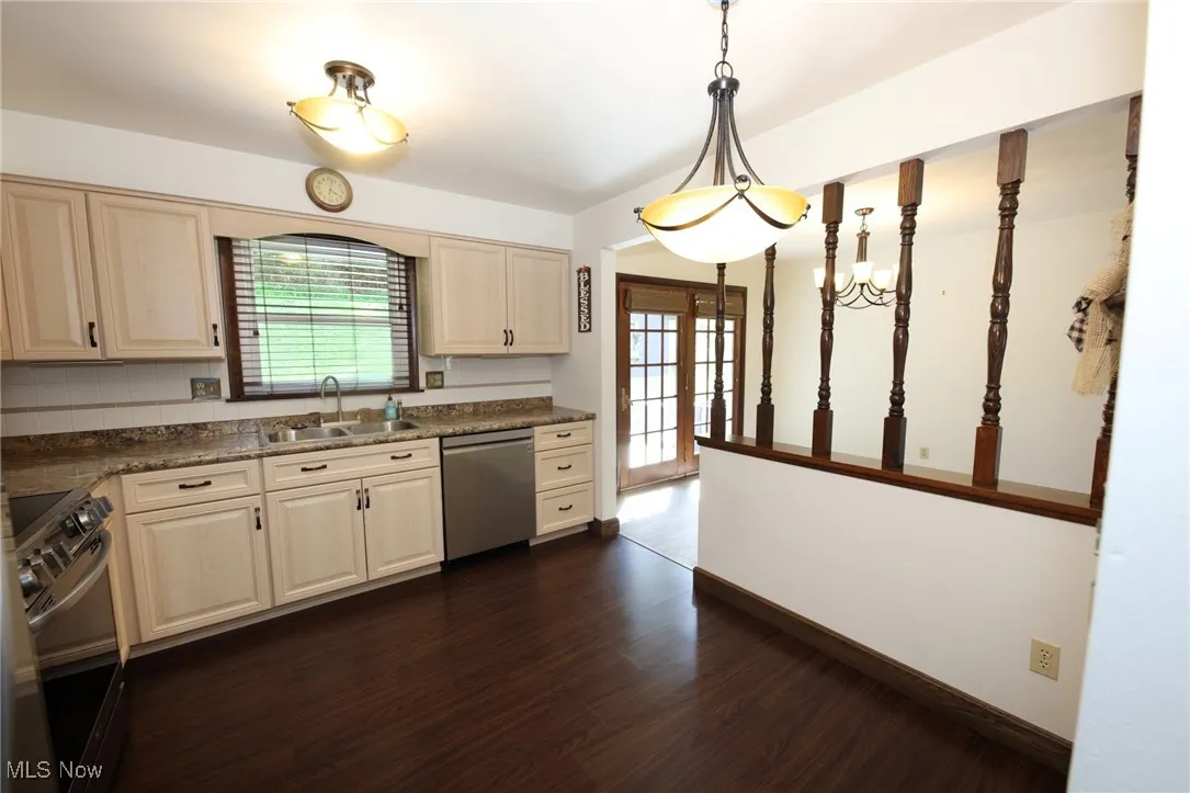 Kitchen with healthy amount of natural light, stainless steel appliances, hanging light fixtures, and dark wood-type flooring