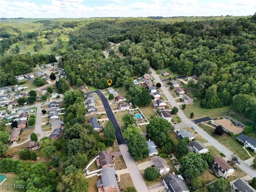 Aerial view of property's location with nearby suburban area and a forest