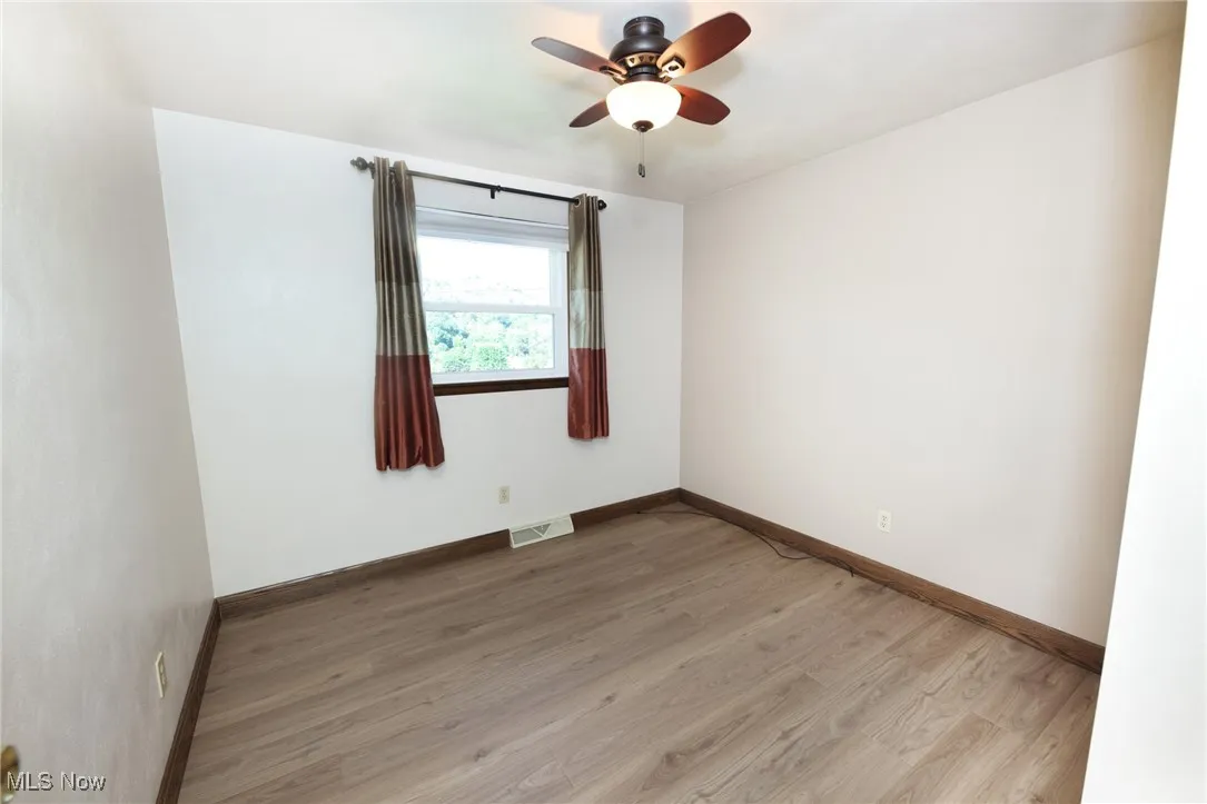 Empty room with light wood finished floors and a ceiling fan