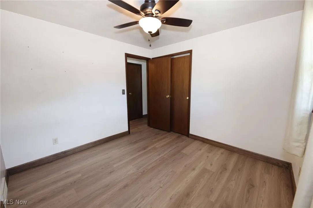 Unfurnished bedroom featuring light wood-style floors, a ceiling fan, and a closet