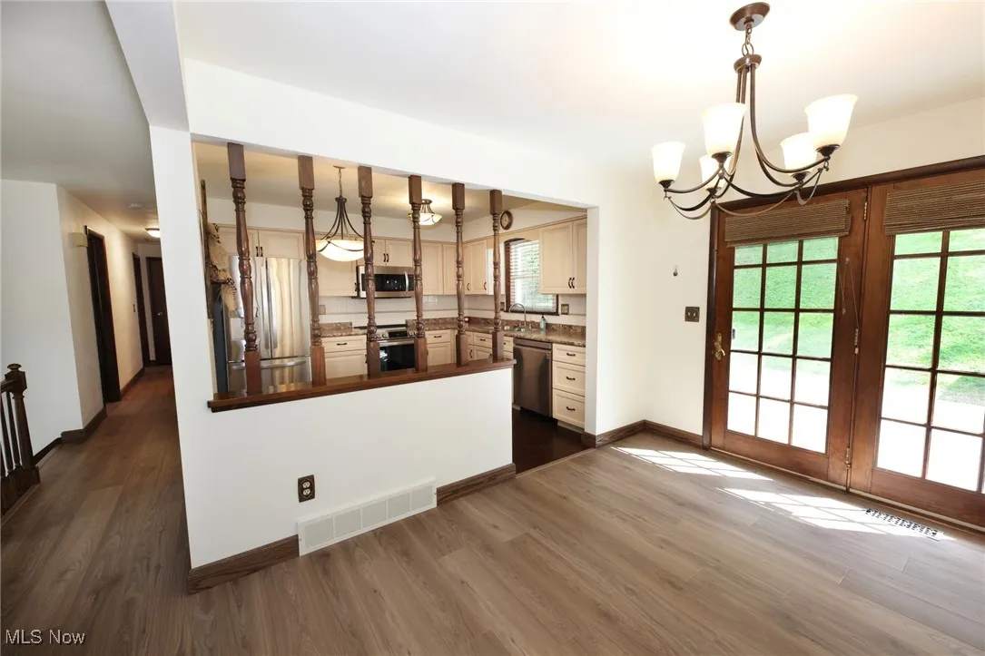 Kitchen featuring pendant lighting, stainless steel appliances, dark countertops, and dark wood-style flooring