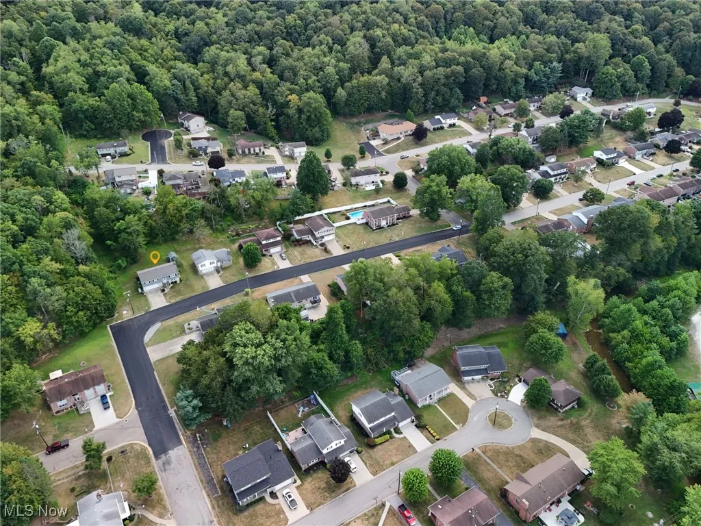 Aerial view of property's location with nearby suburban area and a forest