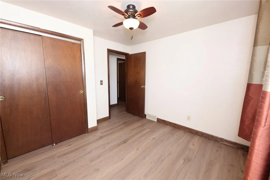 Unfurnished bedroom with light wood-style floors, a closet, and a ceiling fan