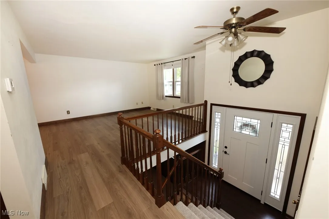 Foyer entrance featuring wood finished floors, stairway, and a ceiling fan