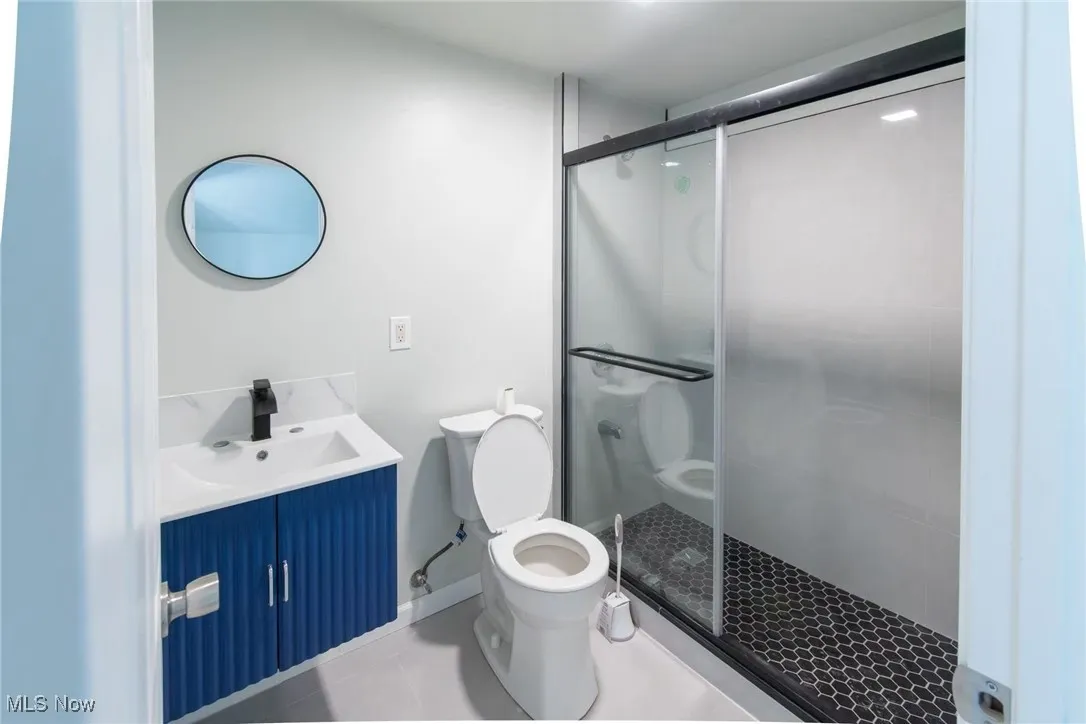 Bathroom with vanity, a stall shower, and tile patterned flooring