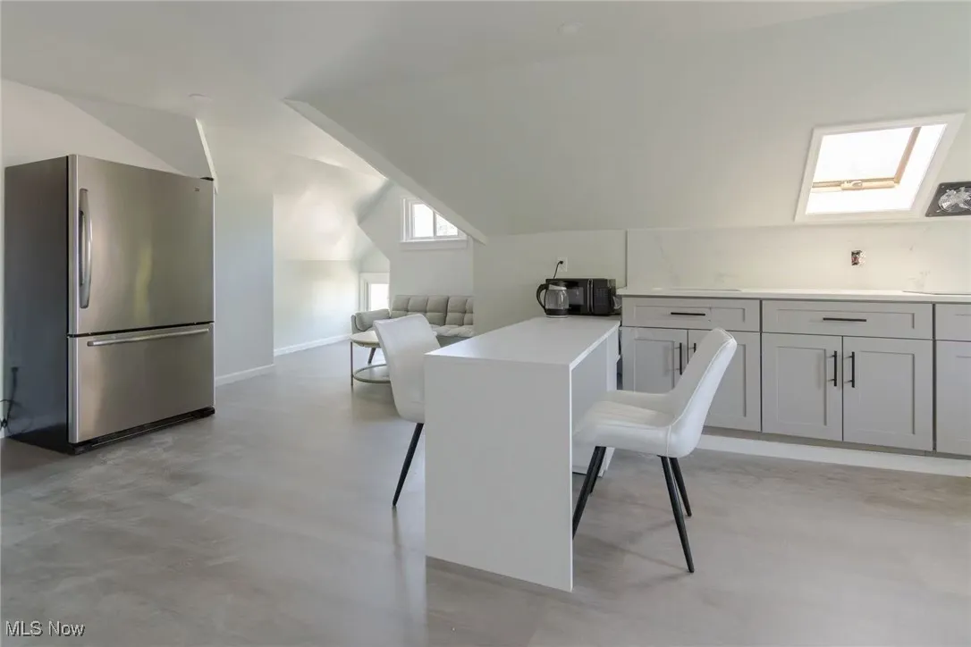 Dining space featuring a skylight, lofted ceiling, and concrete flooring