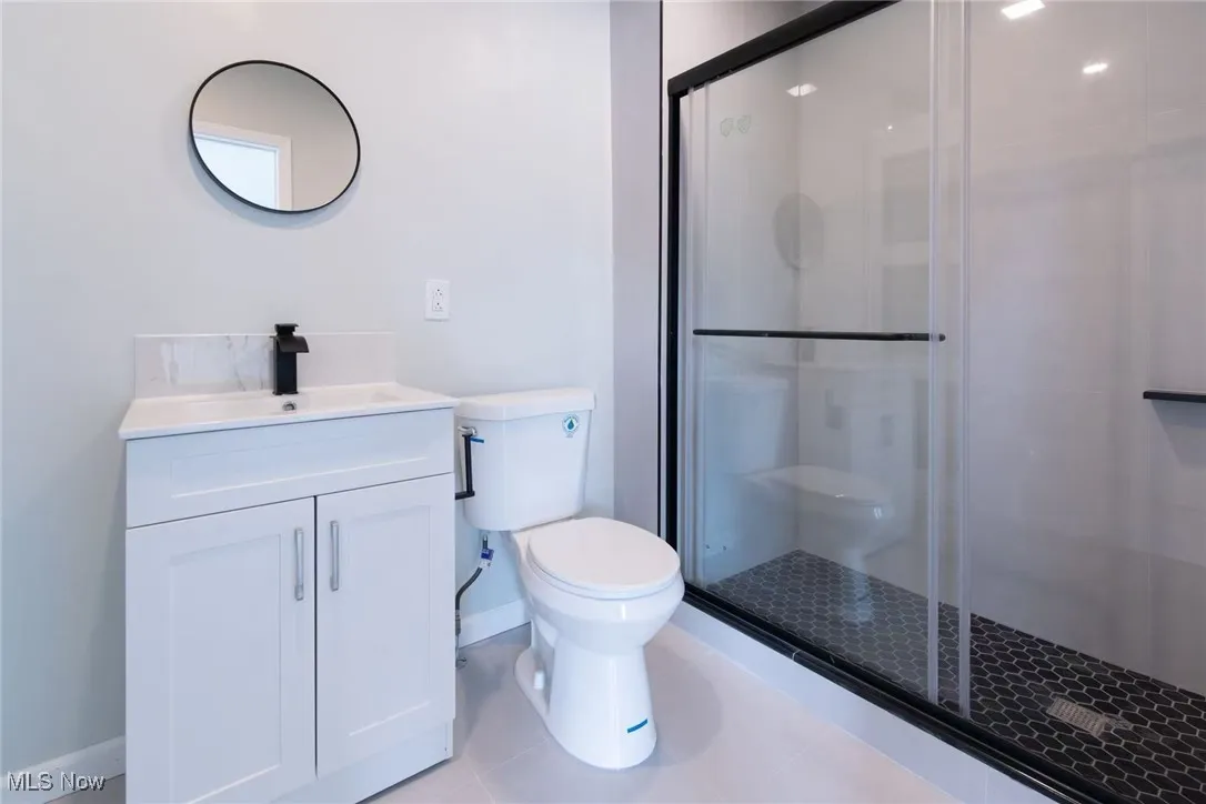 Full bath with vanity, a stall shower, and light tile patterned floors