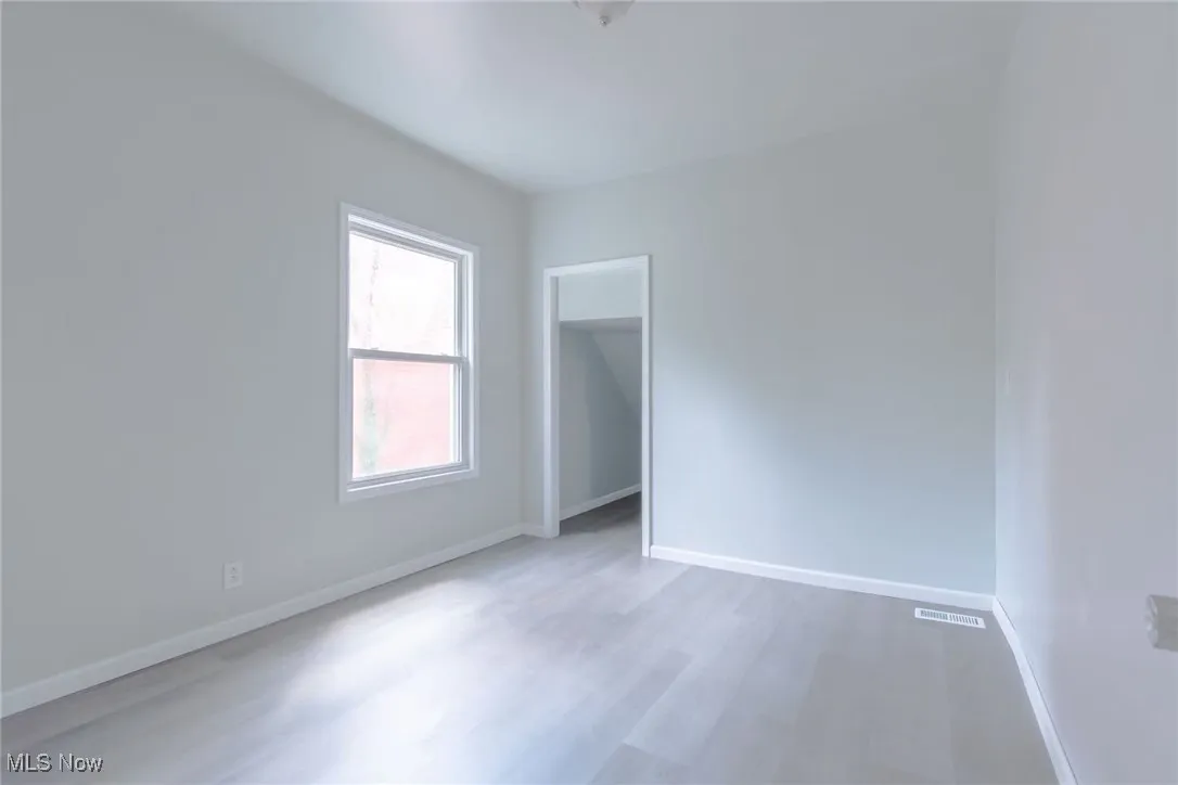 Empty room featuring baseboards and light wood-type flooring
