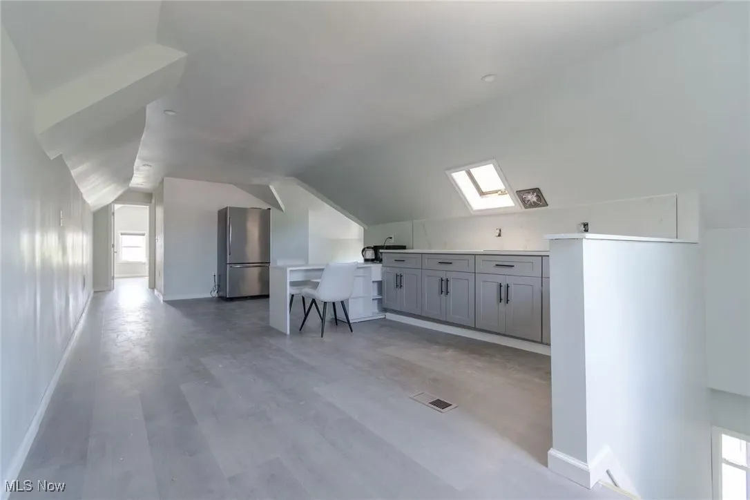 Additional living space featuring lofted ceiling, a skylight, and light wood-style floors