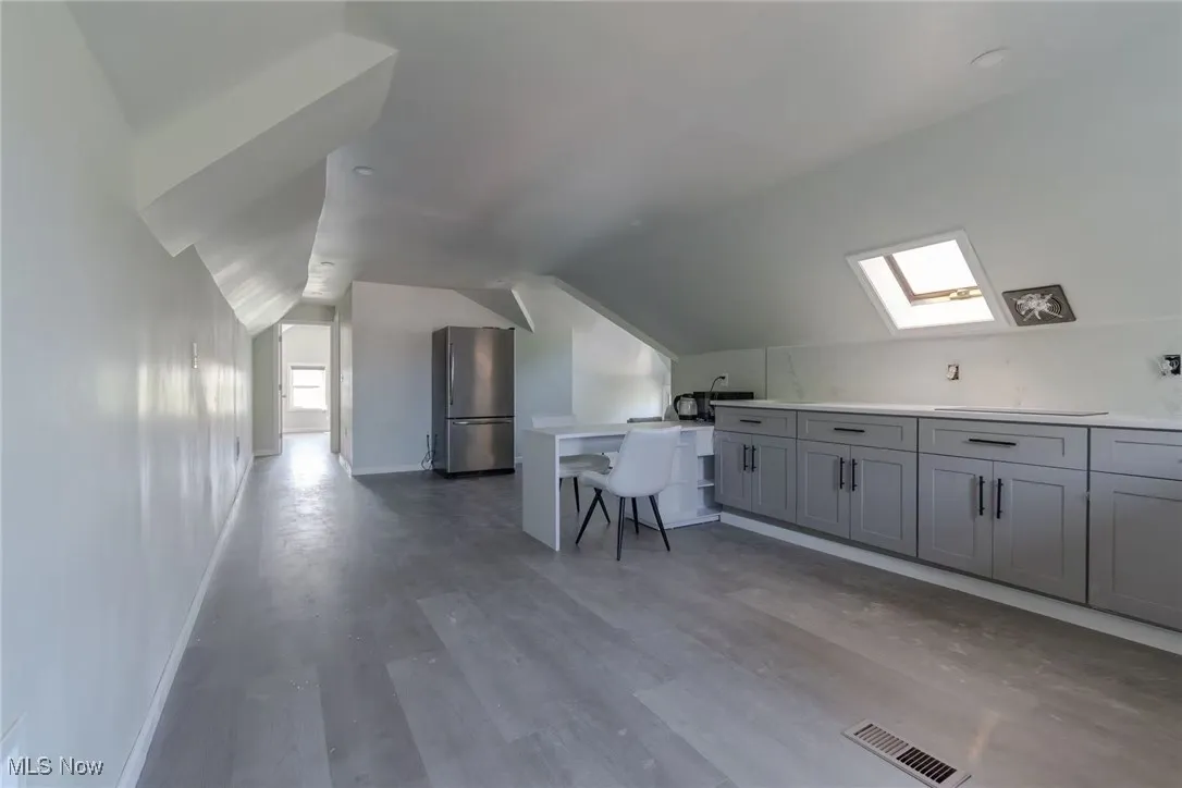 Additional living space with vaulted ceiling, a skylight, and light wood-style floors