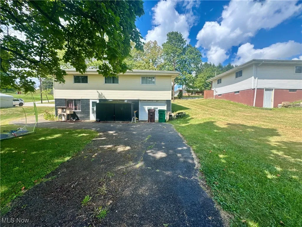 View of side of property with an attached garage, driveway, and a lawn