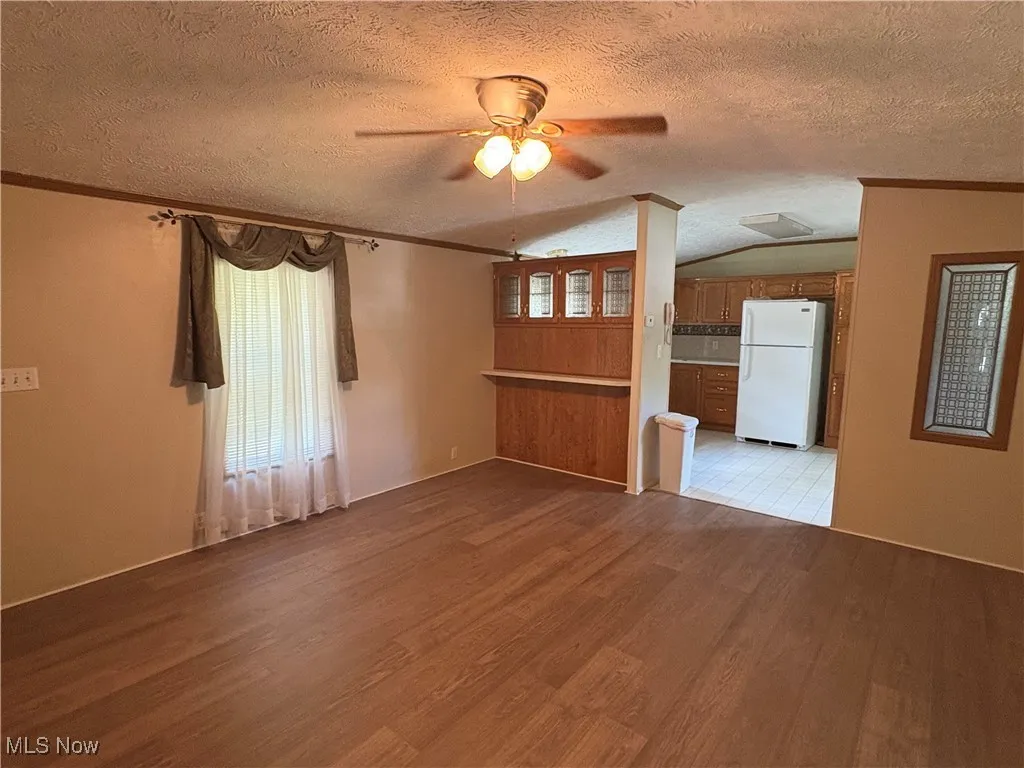 Spare room featuring a textured ceiling, ornamental molding, light wood finished floors, and a ceiling fan