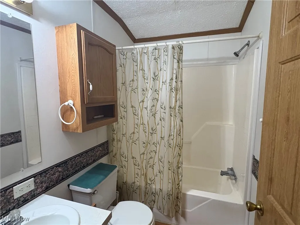 Full bathroom featuring a textured ceiling, shower / bath combo, and vanity