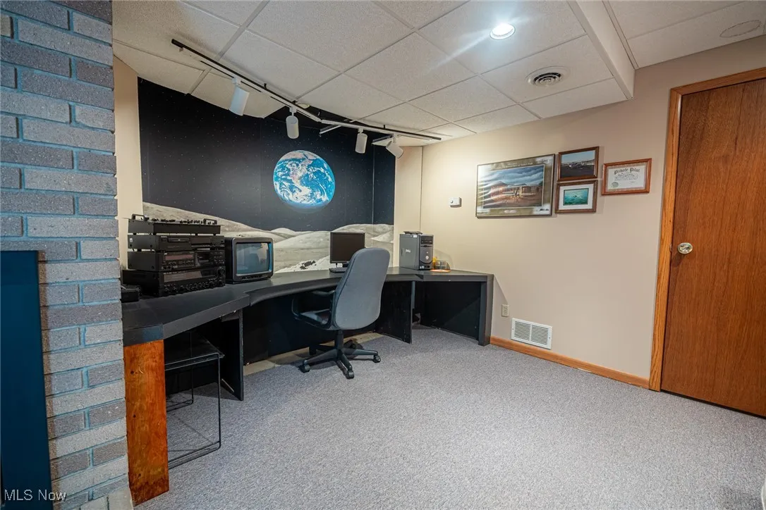 Office area with track lighting, a drop ceiling, and light carpet