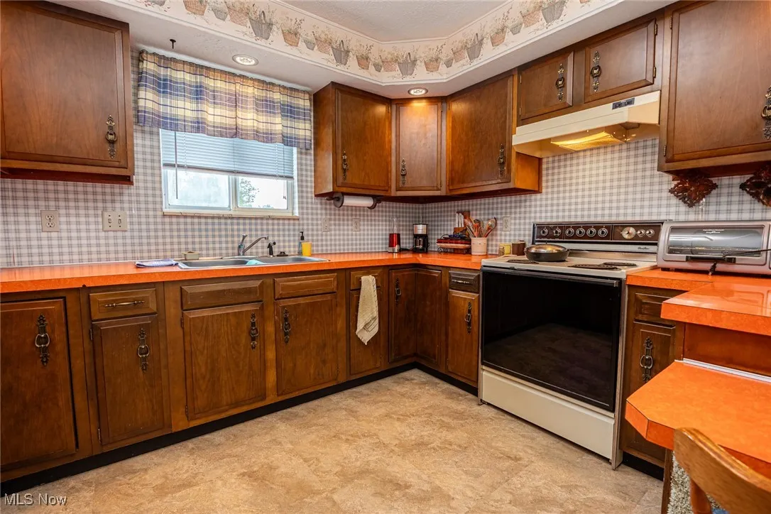 Kitchen with electric stove and under cabinet range hood