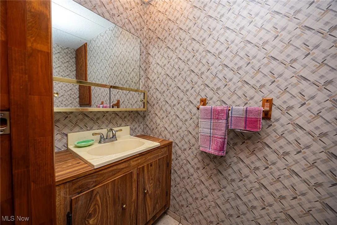 Bathroom with vanity and wallpapered walls