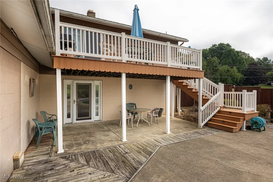 Back of property with a patio, a wooden deck, stairs, outdoor dining space, and a chimney