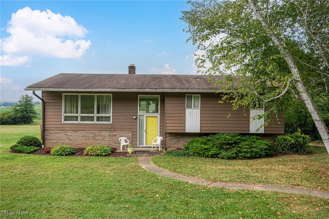 Bi-level home with brick siding, a front lawn, and a chimney