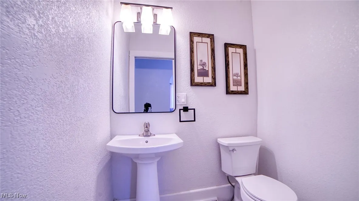 Half bathroom with a textured wall and toilet