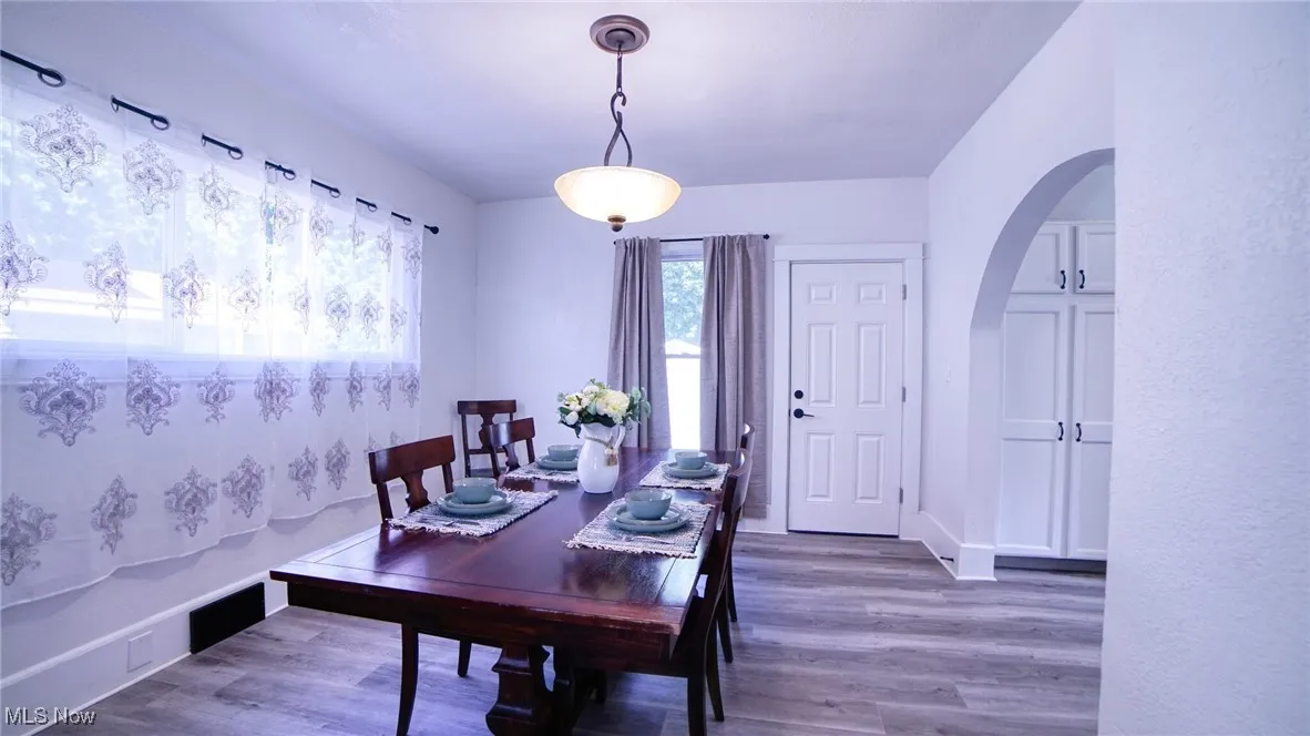 Dining space with arched walkways and wood finished floors
