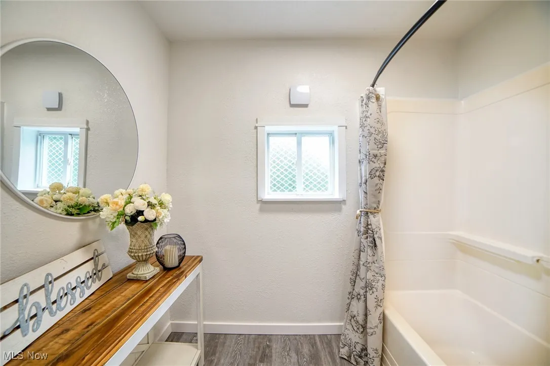 Full bathroom with shower / bath combo, a textured wall, and new lvp flooring