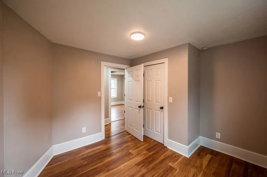 Unfurnished bedroom with dark wood-style flooring and a closet