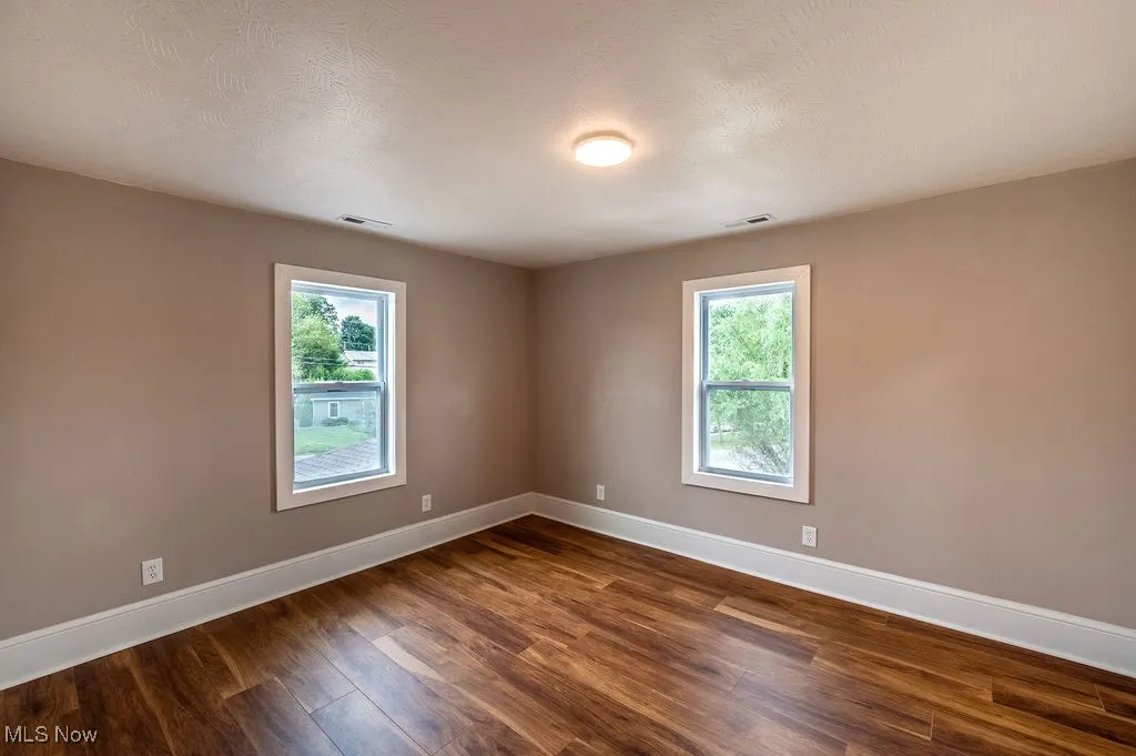 Spare room featuring dark wood finished floors, plenty of natural light, and a textured ceiling