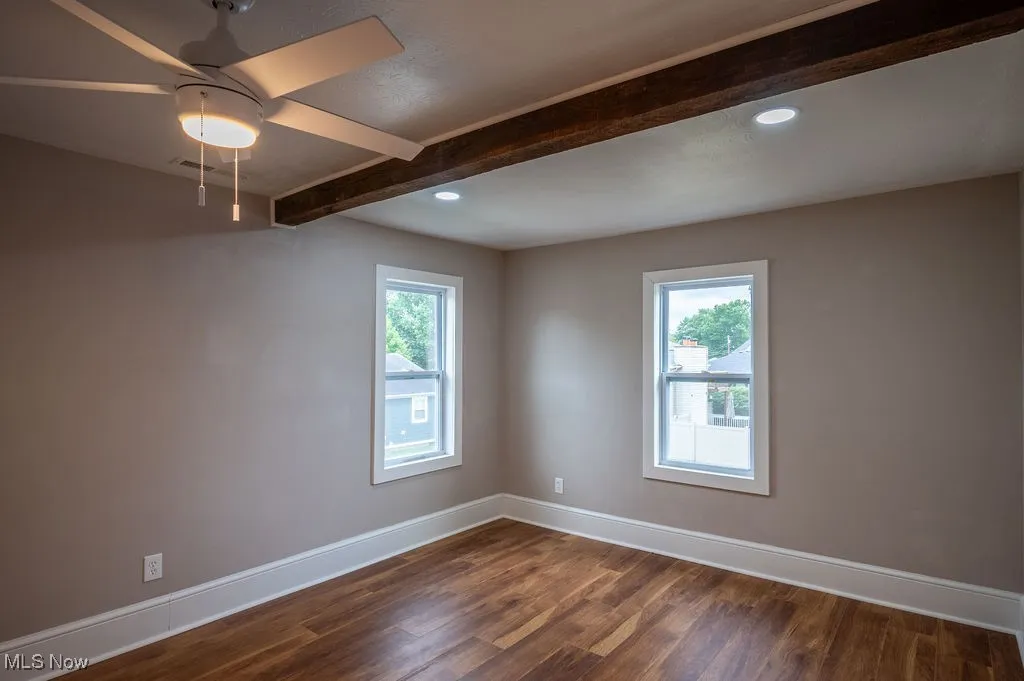 Unfurnished room featuring beamed ceiling, dark wood-style floors, plenty of natural light, recessed lighting, and a ceiling fan
