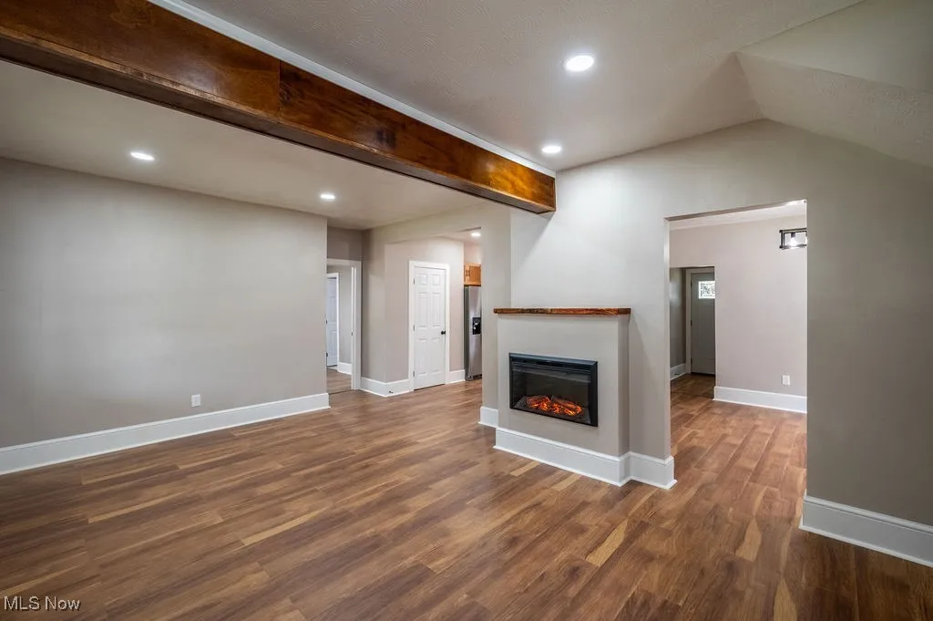 Unfurnished living room with recessed lighting, dark wood-style flooring, and a glass covered fireplace