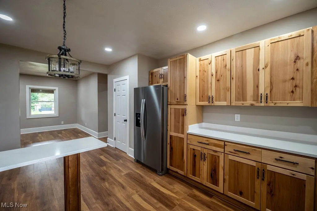 Kitchen featuring stainless steel fridge, decorative light fixtures, dark wood-style flooring, recessed lighting, and light countertops