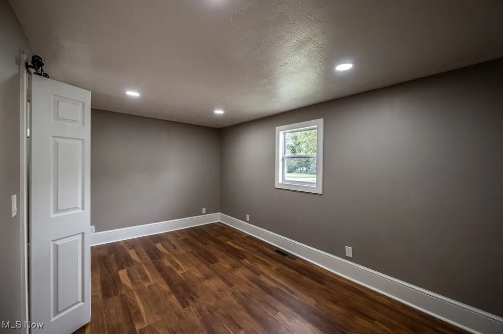 Unfurnished room featuring dark wood-style flooring, a textured ceiling, and recessed lighting
