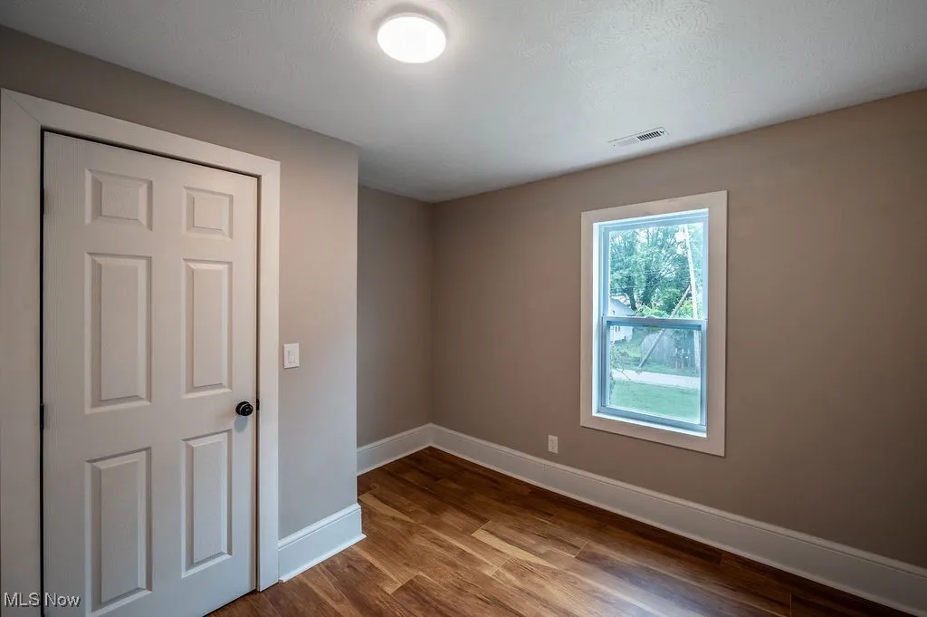 Empty room featuring dark wood-style floors and a textured ceiling