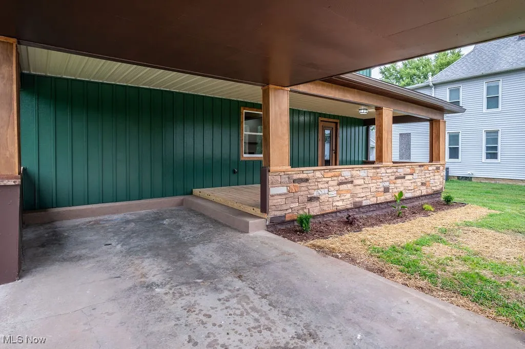 View of exterior entry featuring stone siding, a porch, and board and batten siding