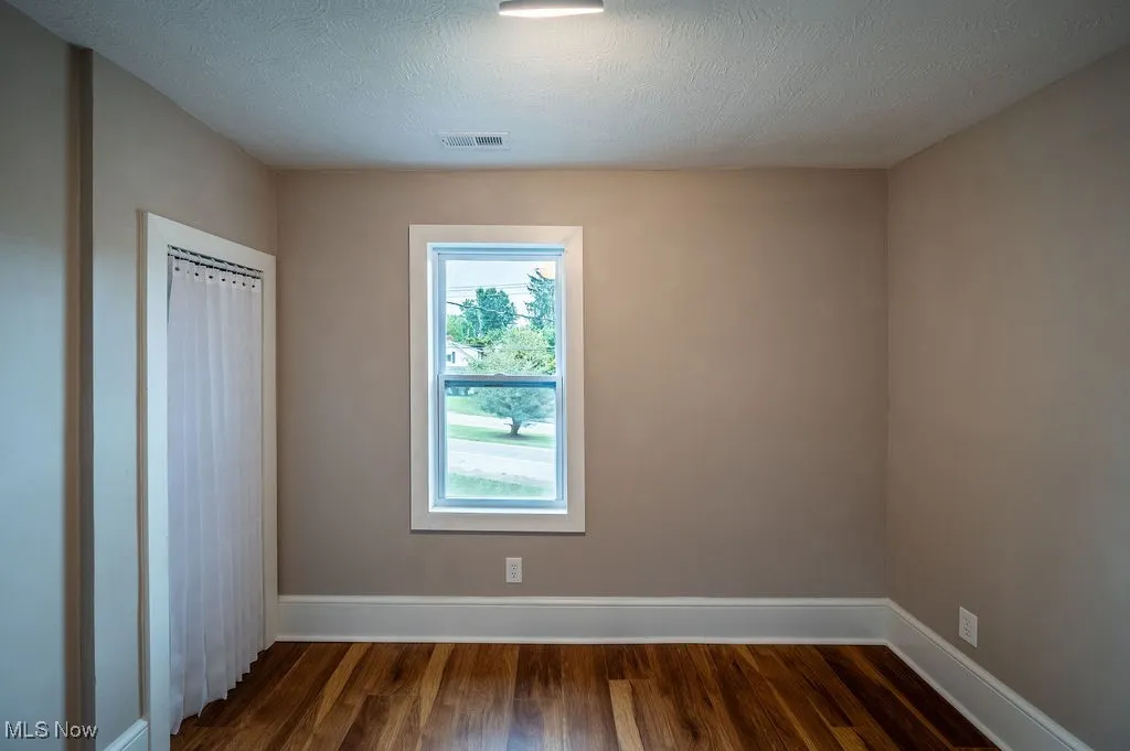Unfurnished bedroom featuring dark wood-style floors, a closet, and a textured ceiling